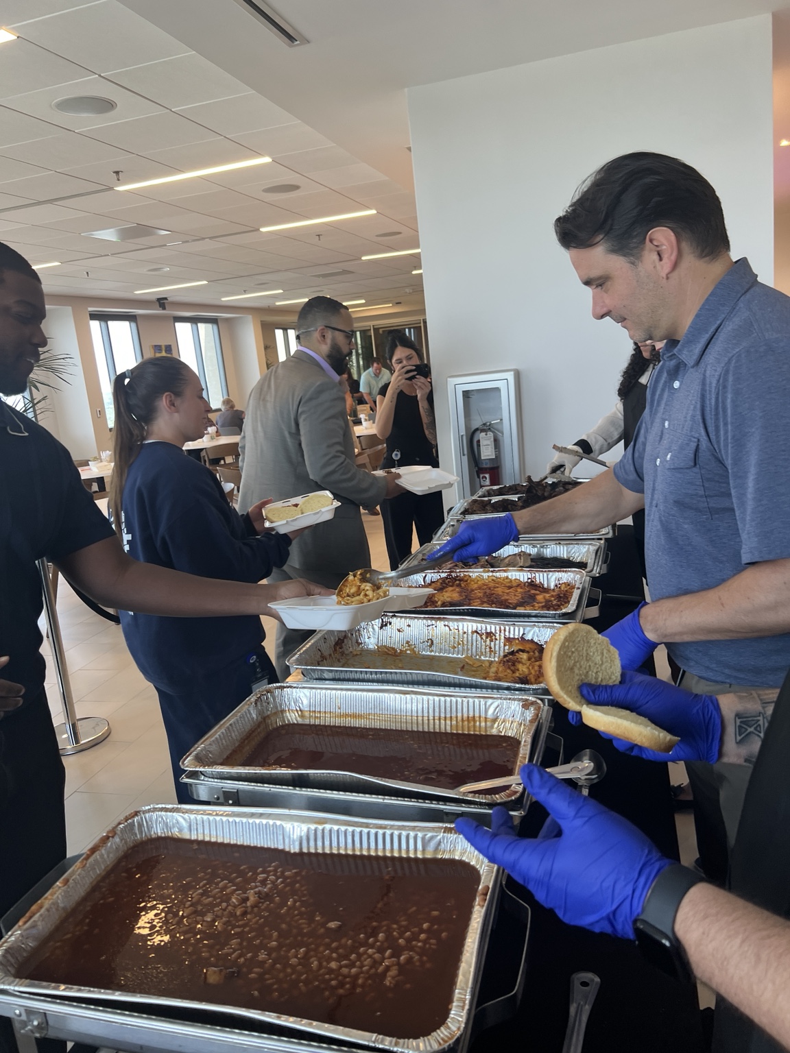Guests being served barbecue and sides at an indoor catered event