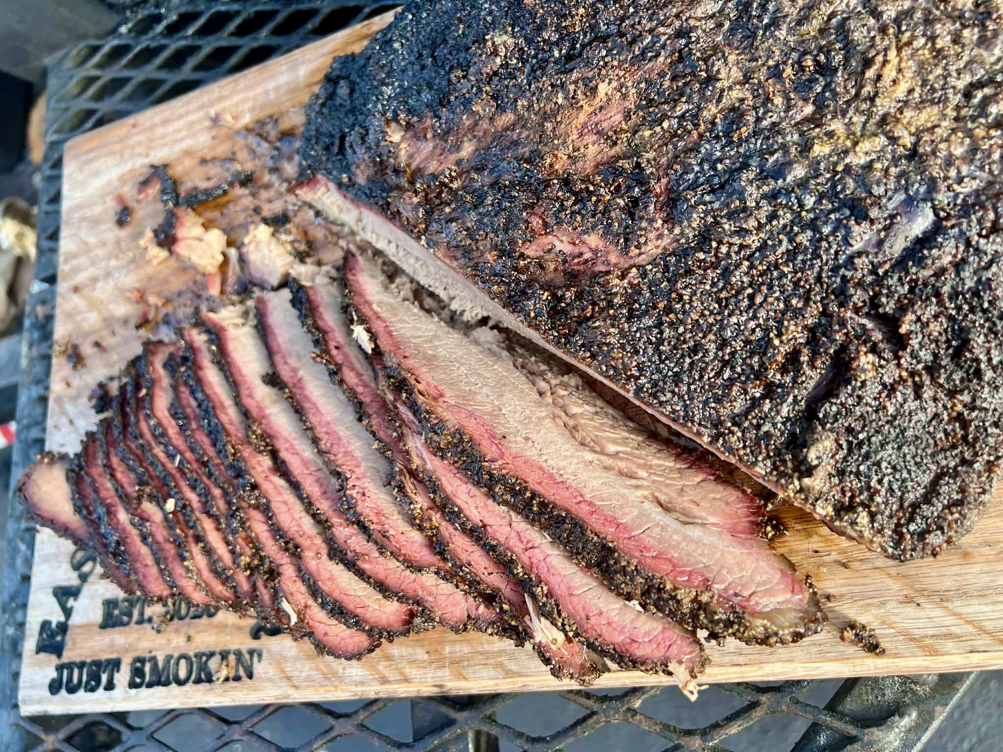 Eastside BBQ sliced brisket with peppery bark and a pink smoke ring on a wooden cutting board